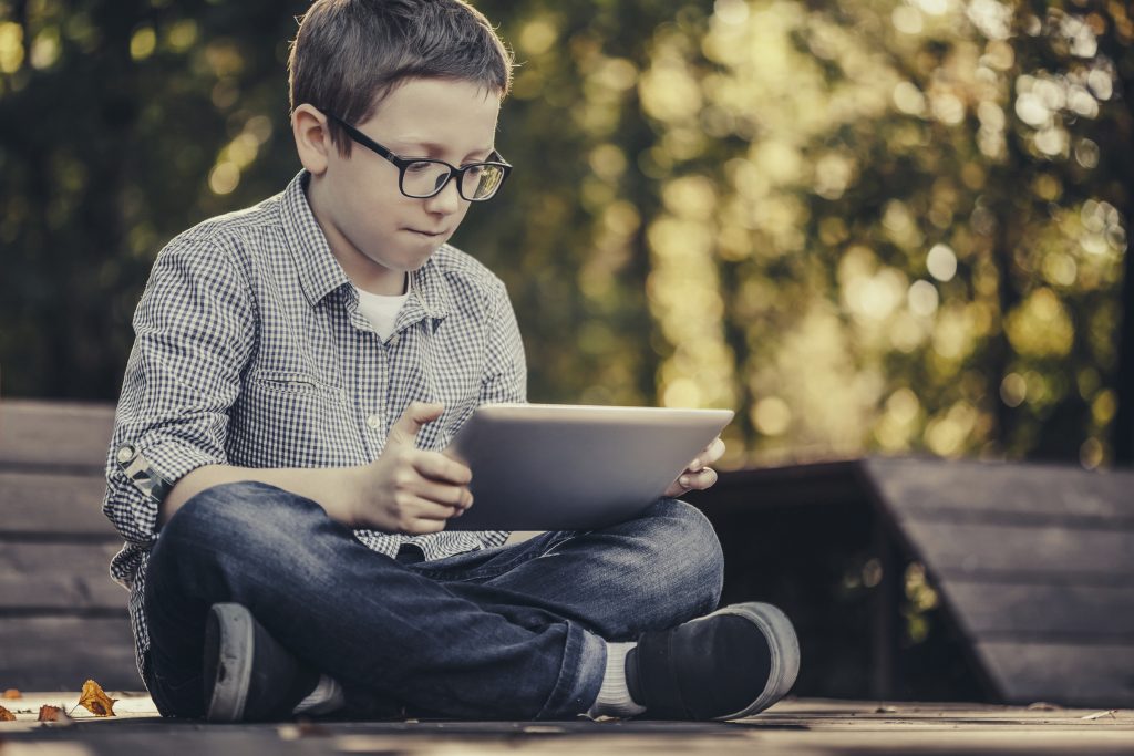 Boy using digital tablet sitting in the park