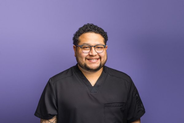 Professional headshot of a man with short dark hair wearing a blue collared shirt